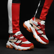 Red and white sneakers with black accents worn with black and red pants on a black background